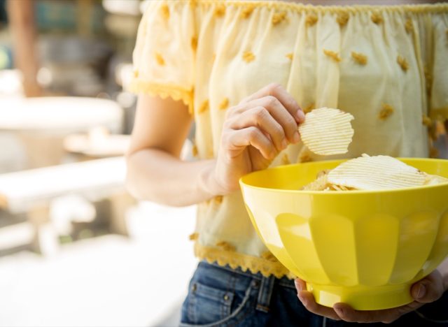 woman in yellow shirt holding yellow bowl of chips
