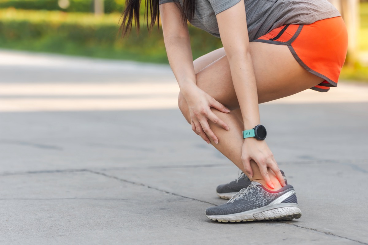 Woman holding her achilles tendon.