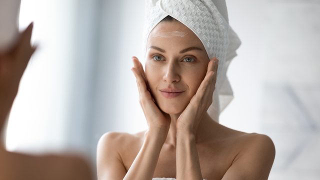 woman looking at her face in the mirror