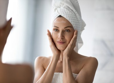 woman looking at her face in the mirror