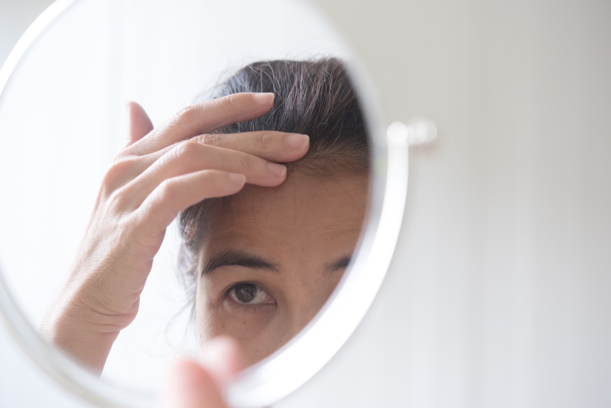 woman looking at wrinkles in mirror