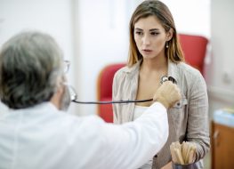 Woman getting her painful chest examined by a doctor.