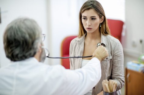 Woman getting her painful chest examined by a doctor.