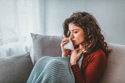 Sick woman with headache sitting under the blanket