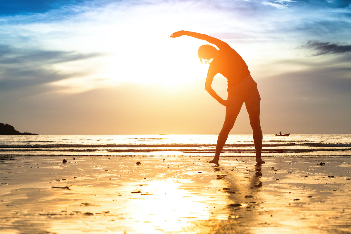 Silhouette young woman, exercise on the beach at sunset