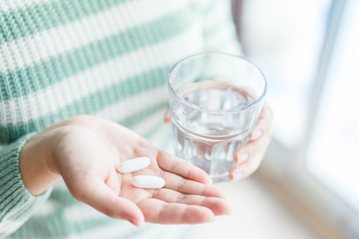 woman in green and white striped shirt taking two pills