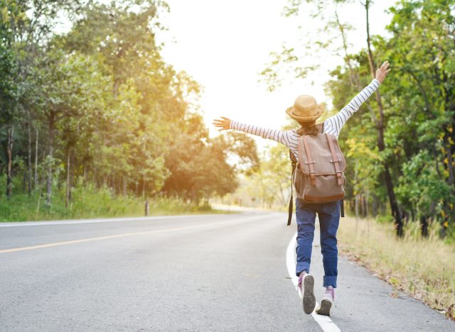 Happy Asian girl backpack in the road and forest background, Relax time on holiday concept travel ,color of vintage tone and soft focus