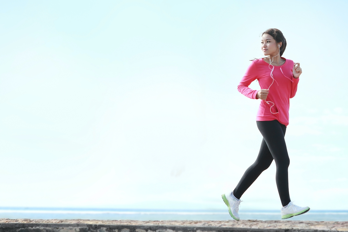 Beautiful healthy woman in pink running on the beach