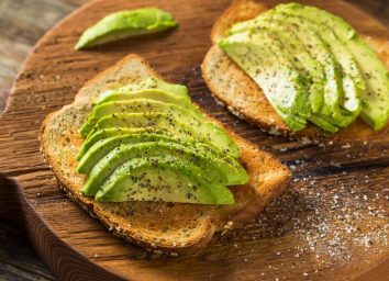 two slices of avocado toast on wooden cutting board