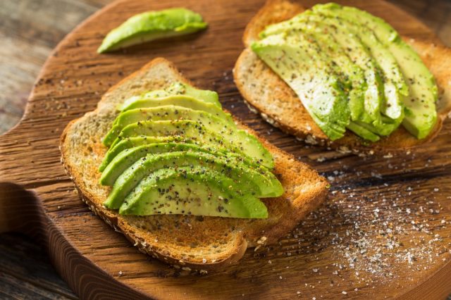 Two slices of avocado toast on a wooden cutting board