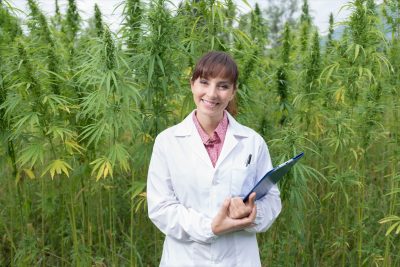 Female doctor with clipboard posing in a hemp field
