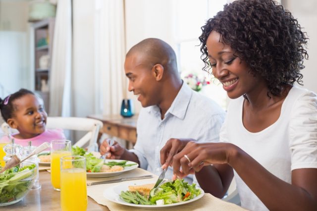 30-something woman and man and a young child eating salad at home