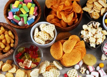 table covered in bowls of popcorn, chips, candy, and other junk foods