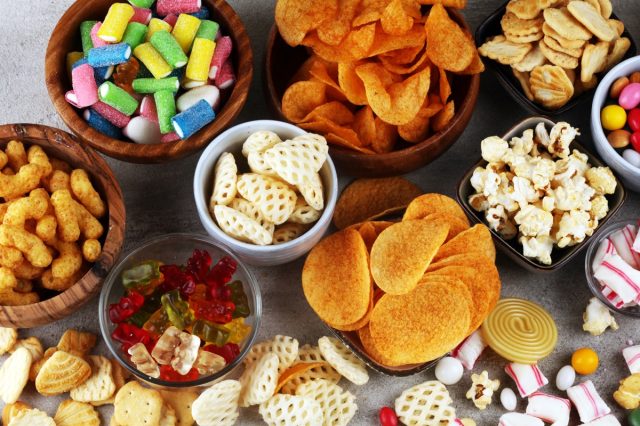 table covered with bowls of popcorn, chips, candy and other junk food