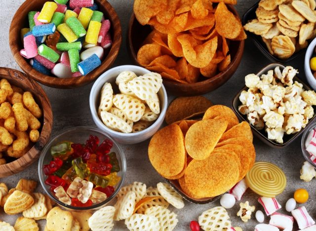 table covered in bowls of popcorn, chips, candy, and other junk foods