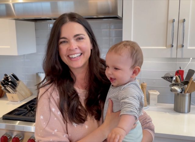 chef katie lee holding her baby daughter iris in a modern kitchen