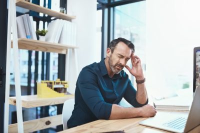 Mature businessman experiencing a headache while working at his desk