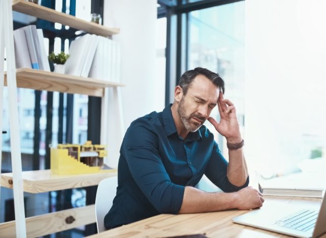 Mature businessman experiencing a headache while working at his desk