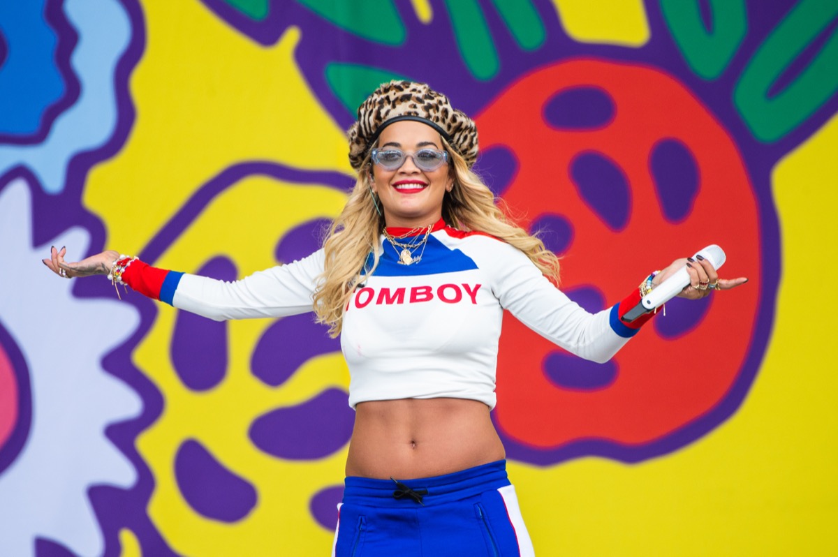 rita ora in a white crop top and blue pants on stage