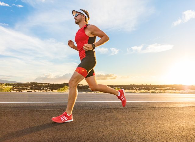 Triathlon - Triathlete man running in triathlon suit training for ironman race. Male runner exercising on Big Island Hawaii. Sunset.