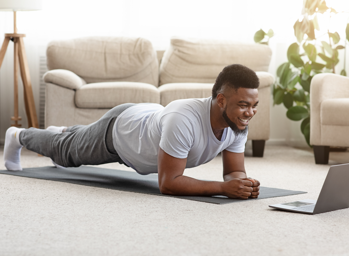 man in home doing modified plank on yoga mat in living room
