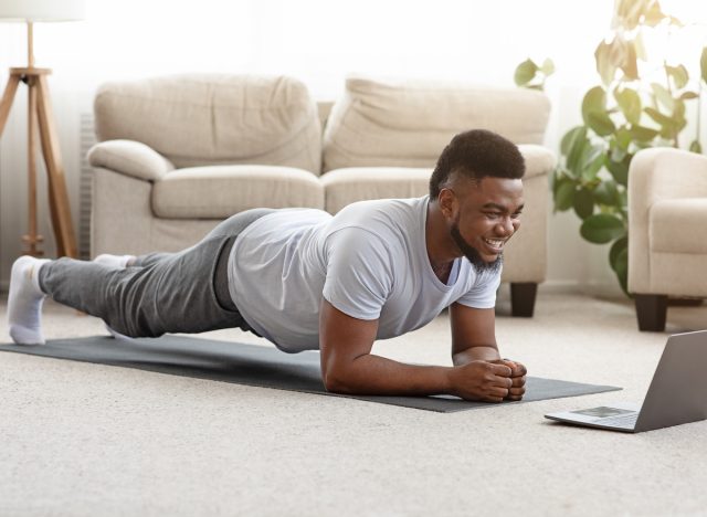 1700797540 man in home doing modified plank on yoga mat in living room