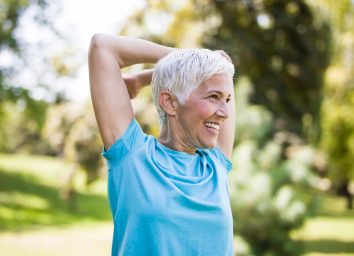 Senior woman with short hair stretching arms