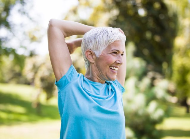 Senior woman with short hair stretching arms