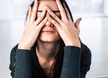 young woman covering her face with her hands