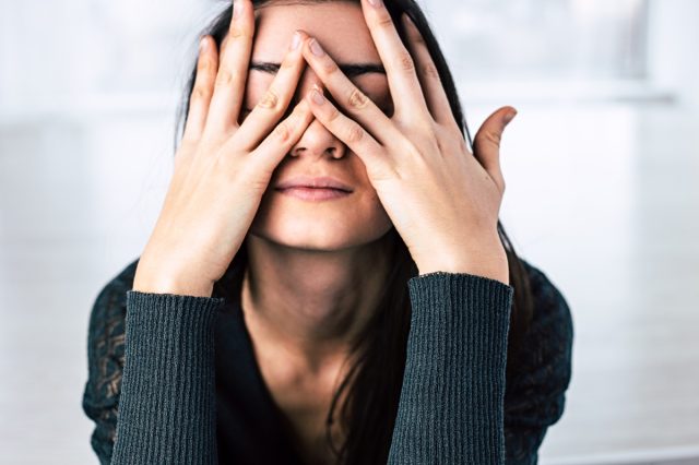 young woman covering her face with her hands