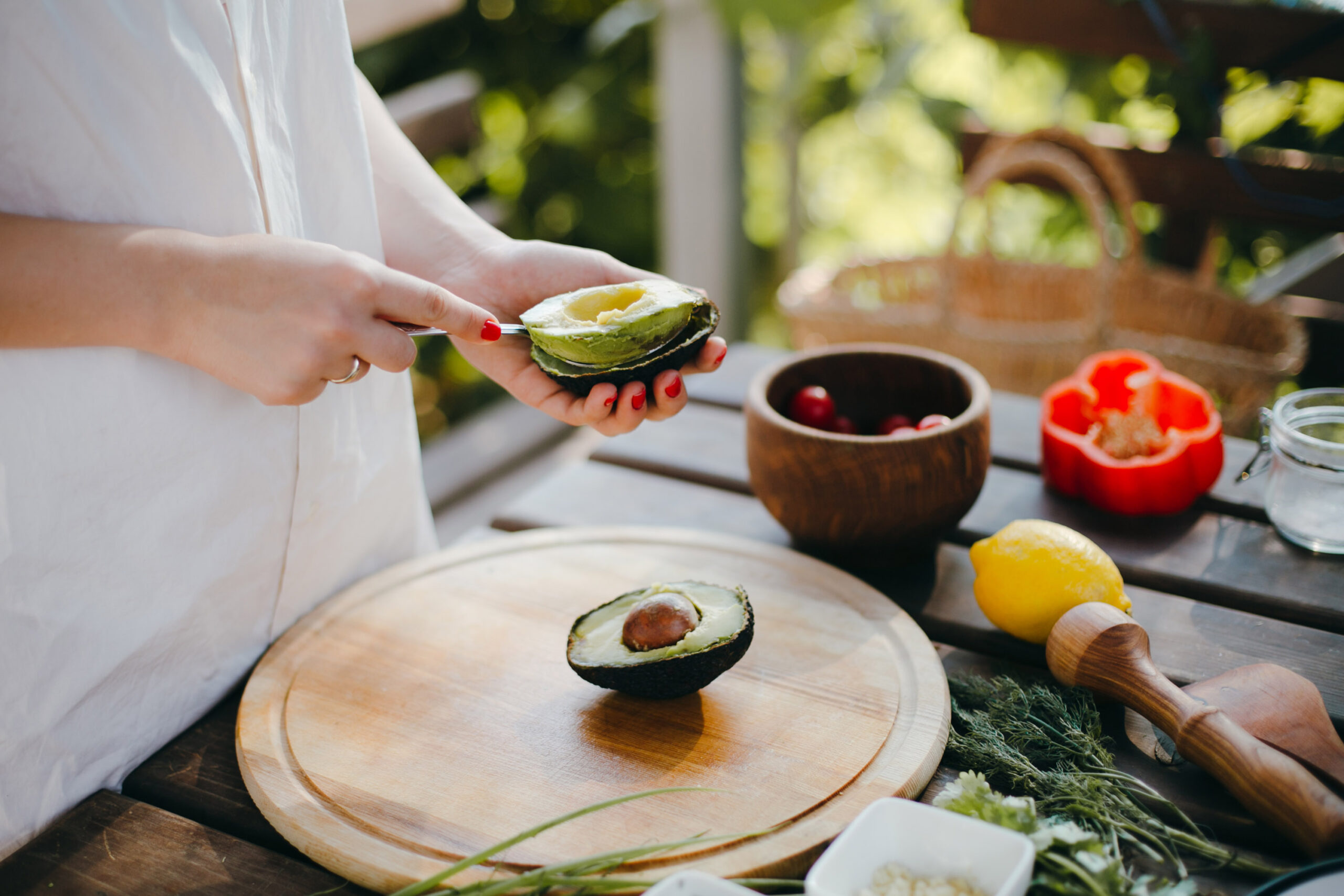 Woman's,Hands,Peeling,Avocado,For,Guacamole,With,A,Spoon.,Picnic