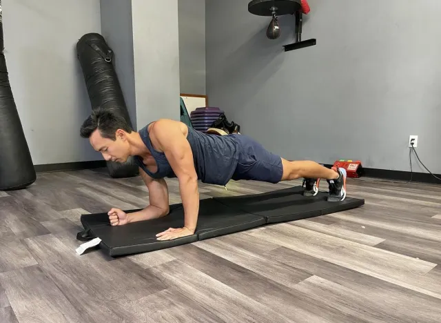 trainer doing plank to pushup on mat