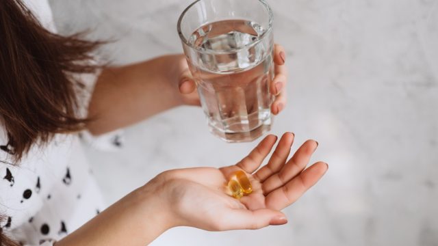woman taking vitamin d supplement with water