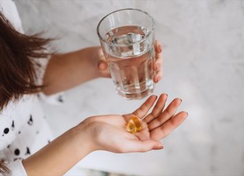 woman taking vitamin d supplement with water