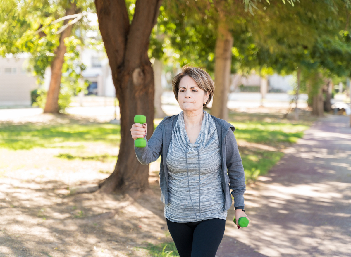 older woman walking with hand weights