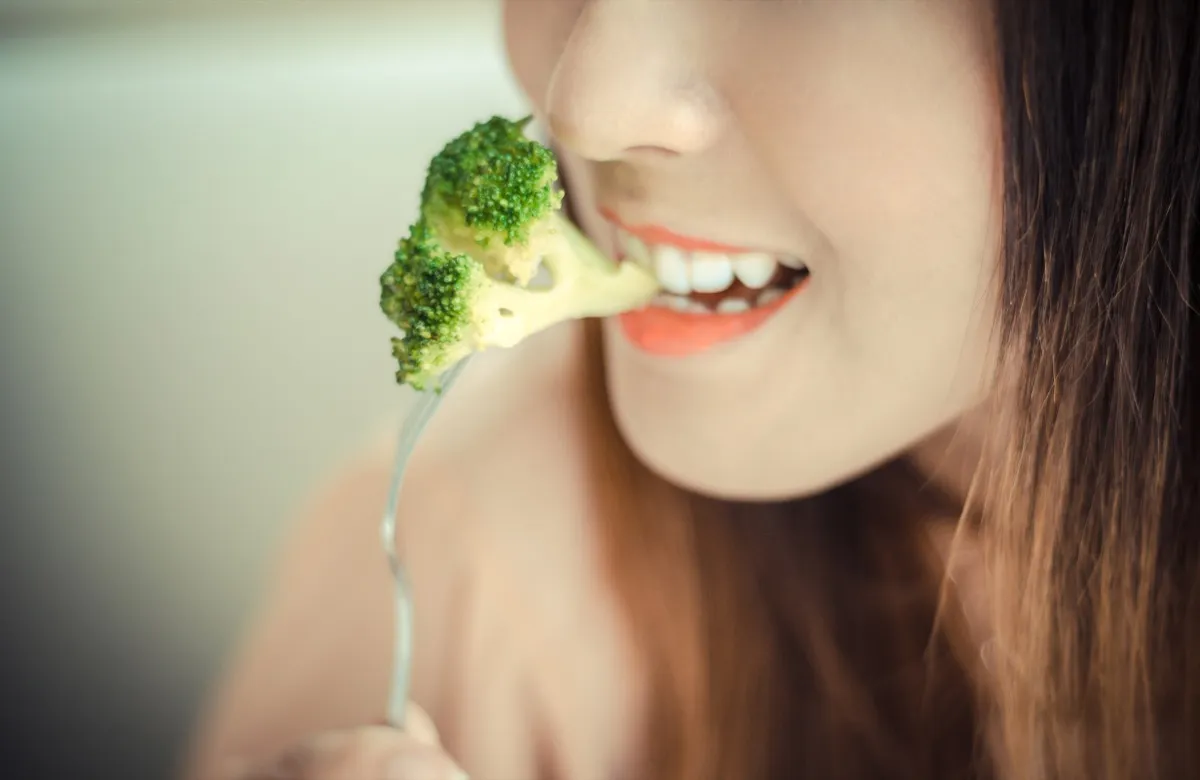 young woman eating broccoli