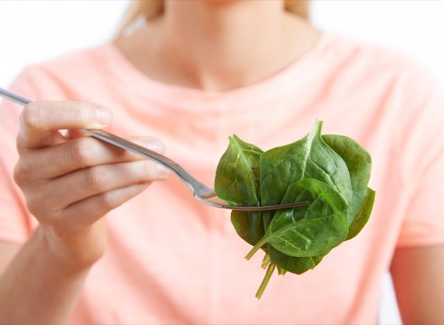 woman eating raw spinach on fork