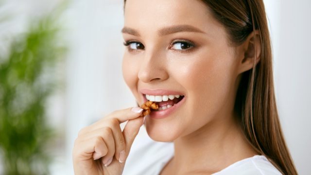 Smiling woman eating nuts.