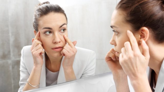 Woman checking wrinkles in front of the mirror.