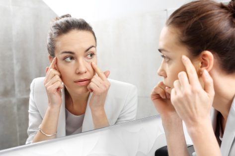 Woman checking wrinkles in front of the mirror.