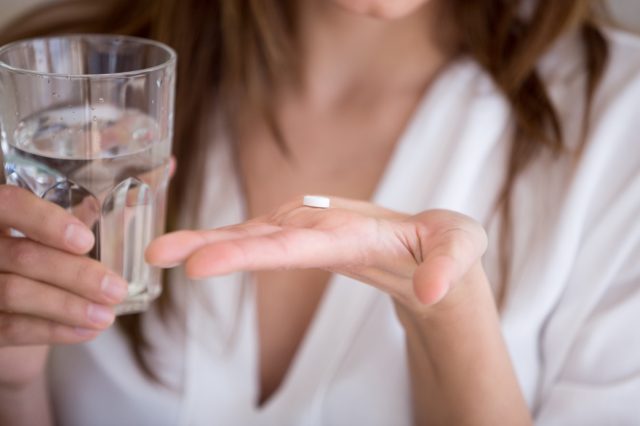 woman taking a pill with water