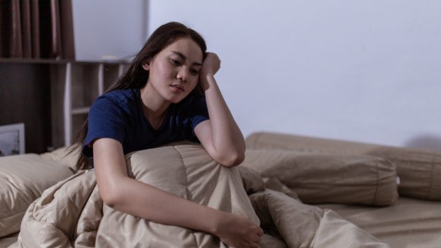 young woman sitting up in bed unable to fall asleep