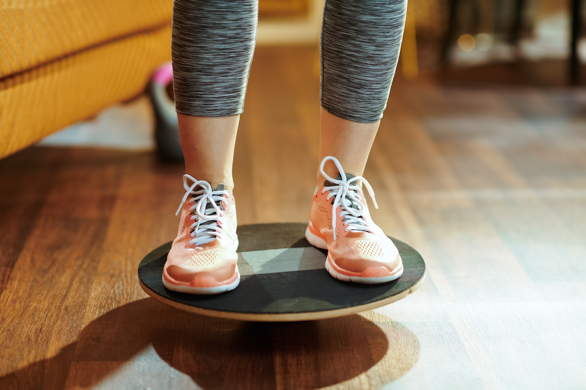 Closeup on fit sports woman in fitness clothes at modern home while training using balance board.