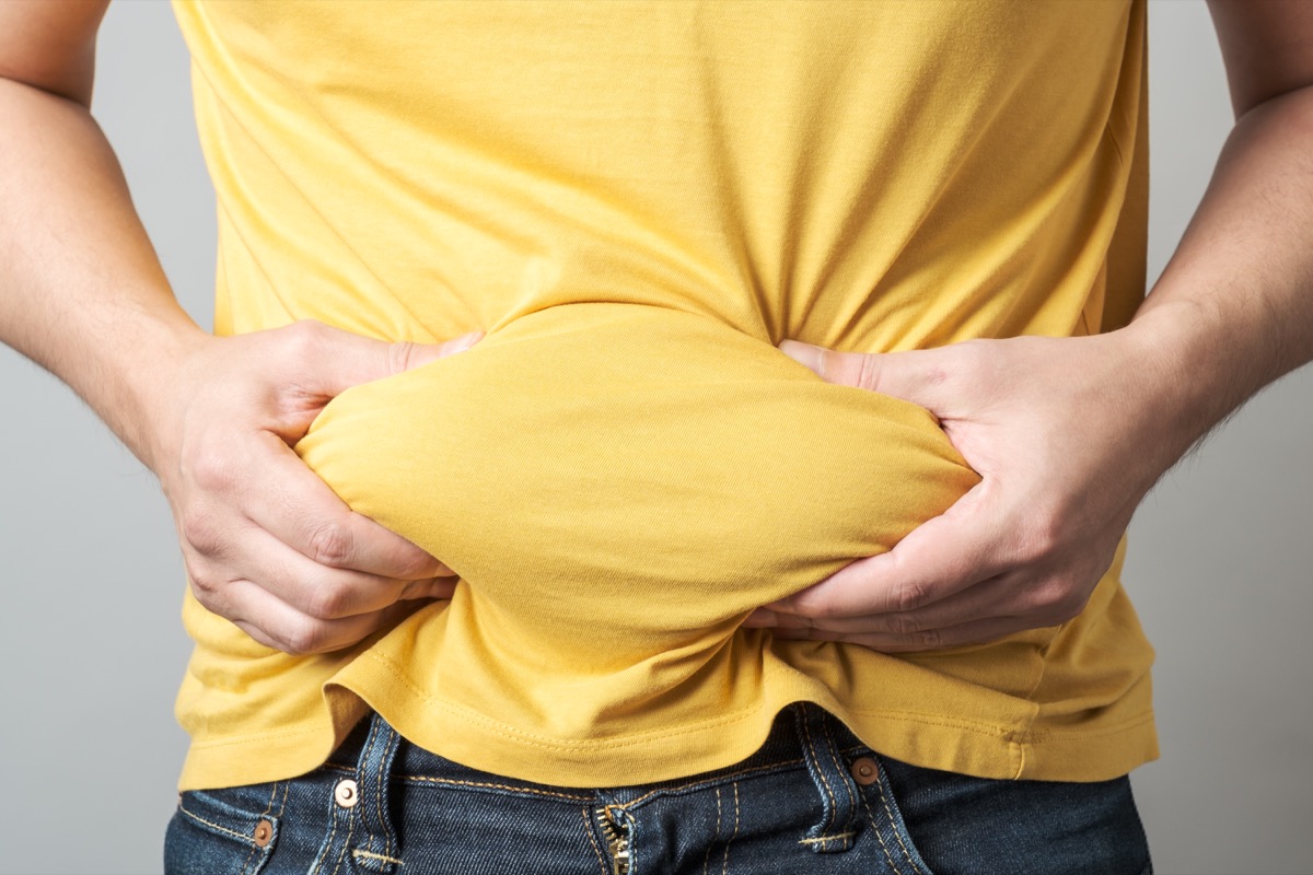 Overweight obese man's hand holding his belly.