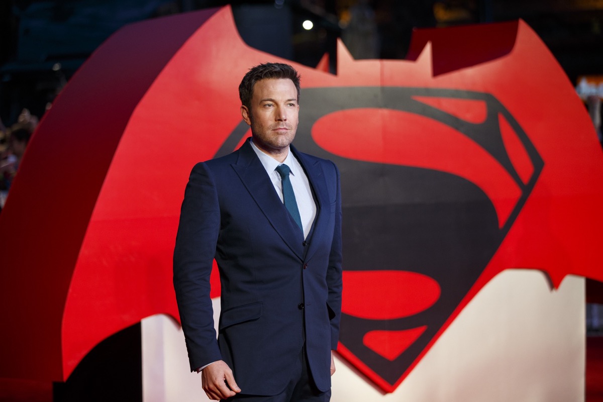 ben affleck in front of batman vs superman sign in blue suit