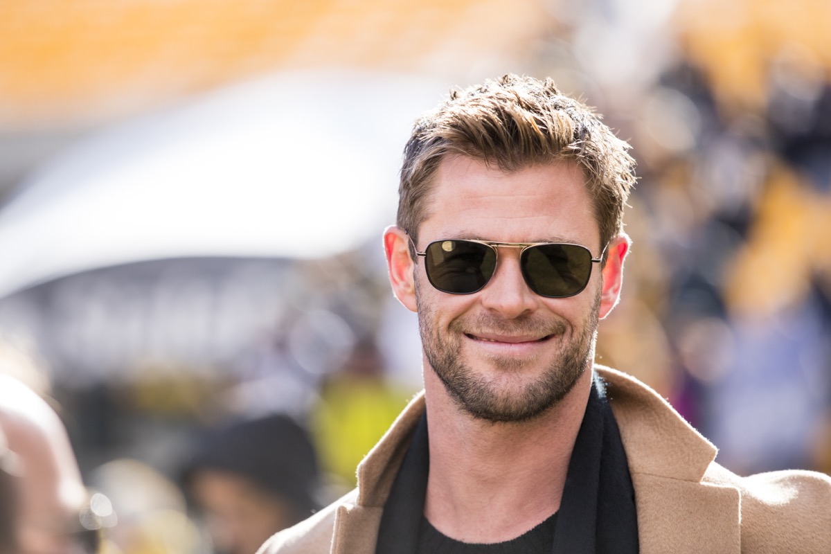 chris hemsworth smiling in a tan coat and sunglasses