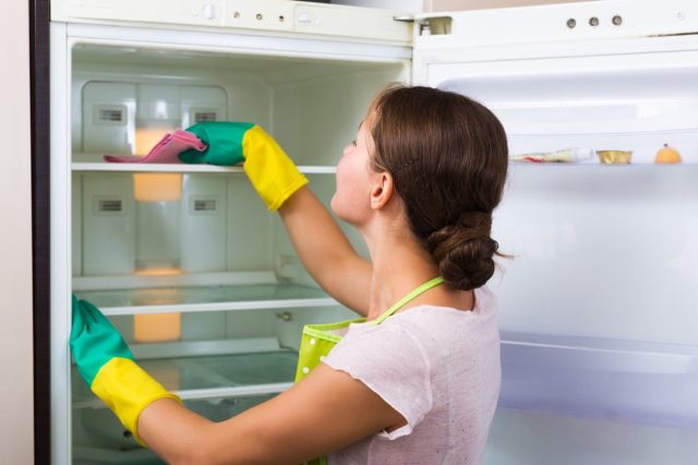 woman cleaning inside of fridge