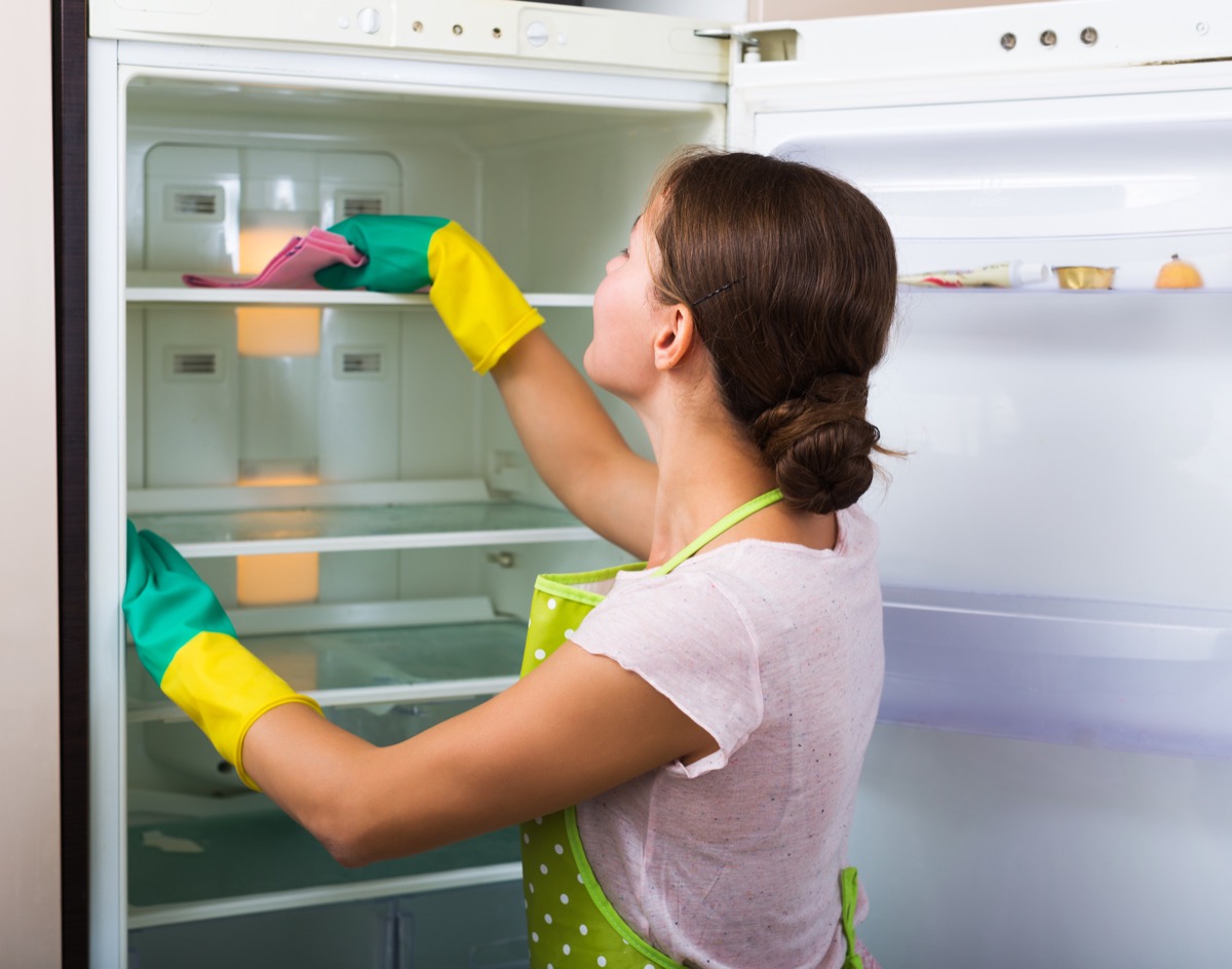 woman cleaning inside of fridge