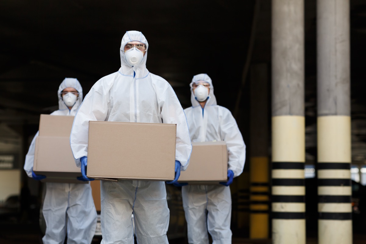 People in protective suits and masks delivering vaccine of coronavirus.