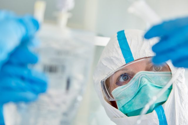 Doctor in protective clothing in hospital intensive care unit prepares Covid-19 patient for infusion during coronavirus pandemic